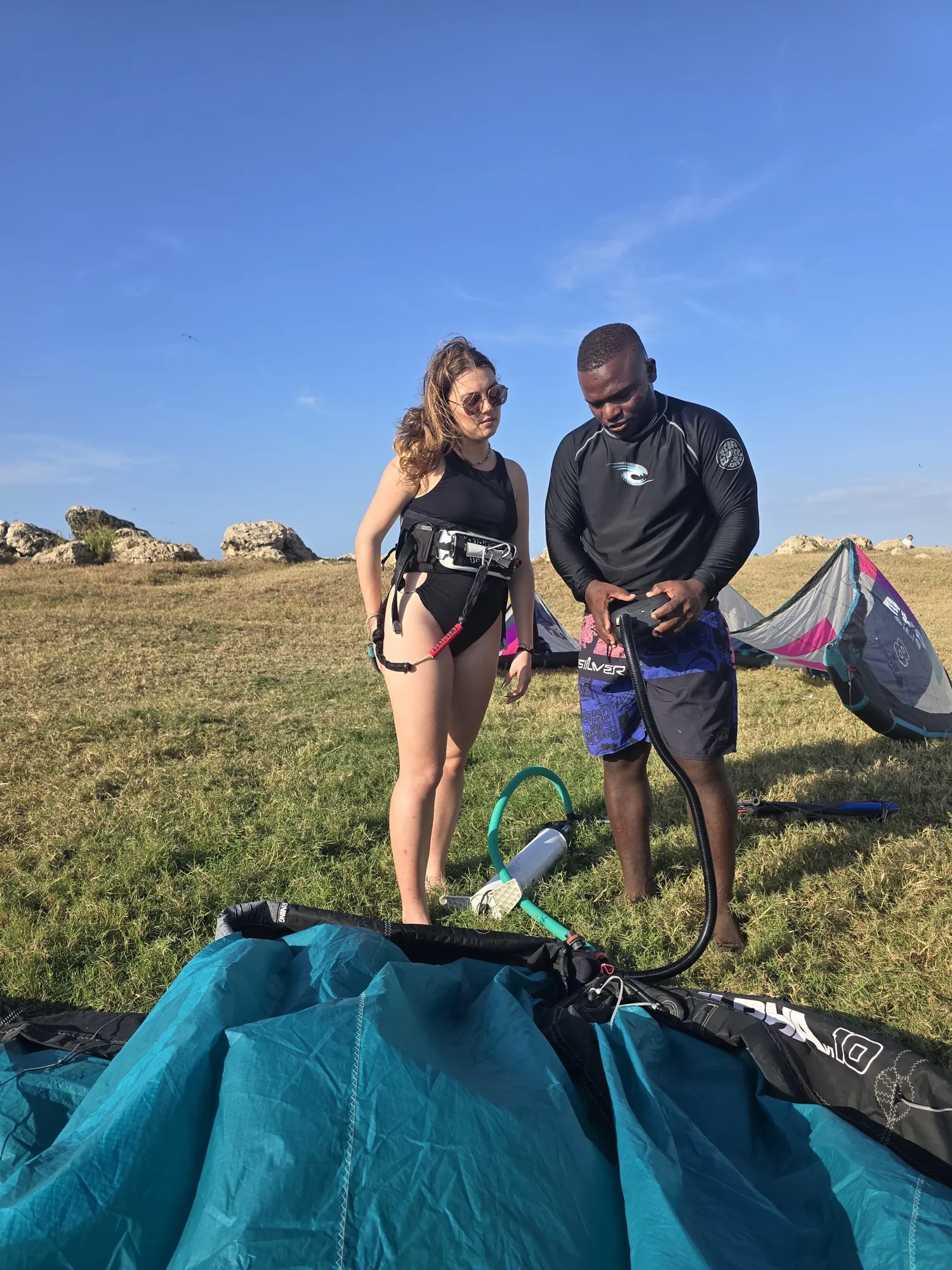 Instructor ajustando arnés de kitesurf a estudiante en la playa de Cartagena antes de la clase