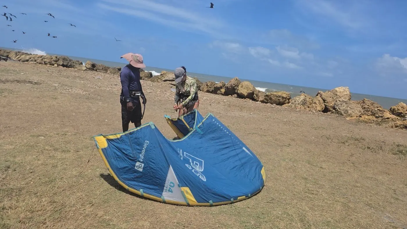 Preparación de equipo de kitesurf en la playa con aves marinas sobrevolando la costa de Cartagena