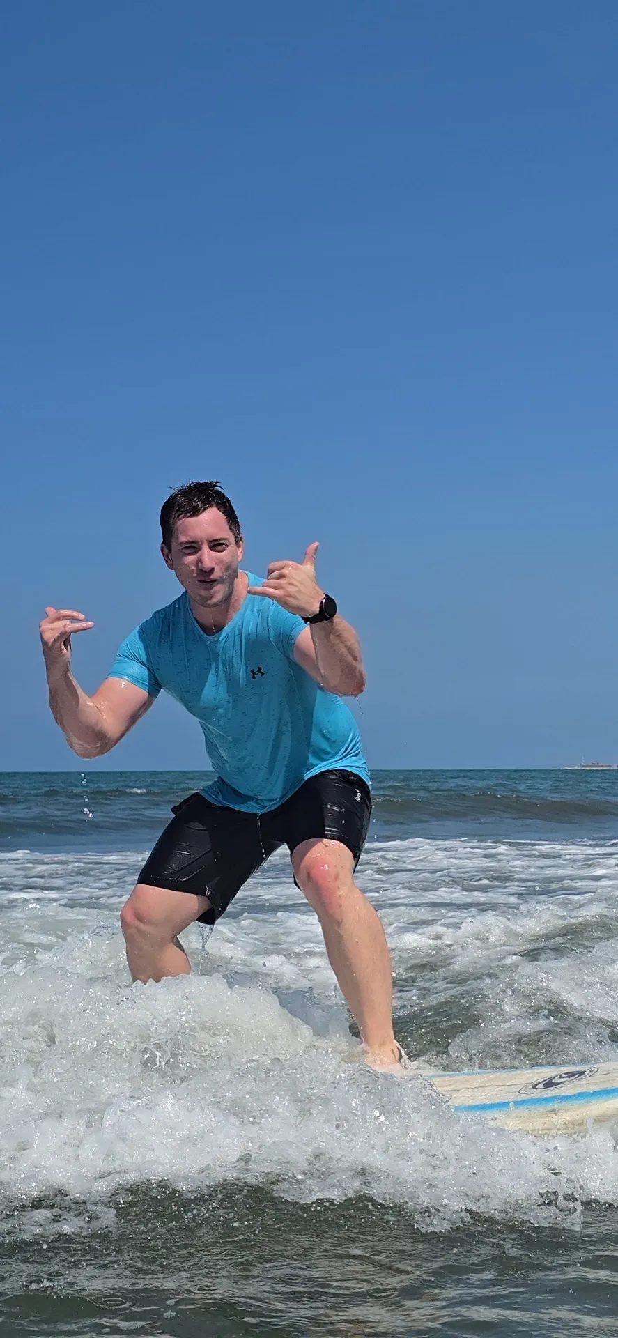 Surfista haciendo shaka en aguas color cyan